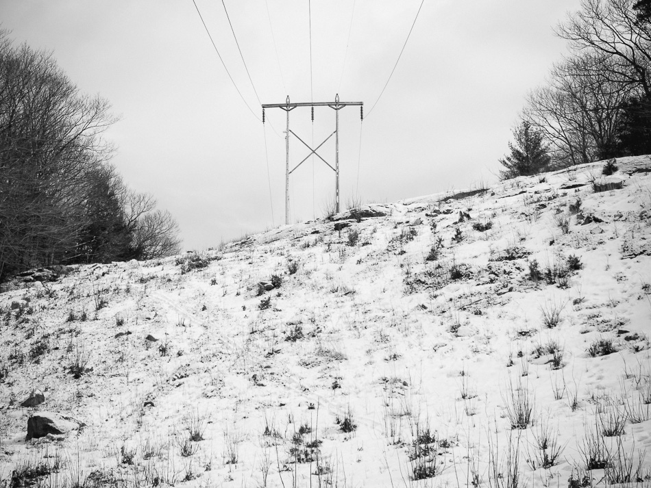 Electrical transmission tower atop a snow covered hill