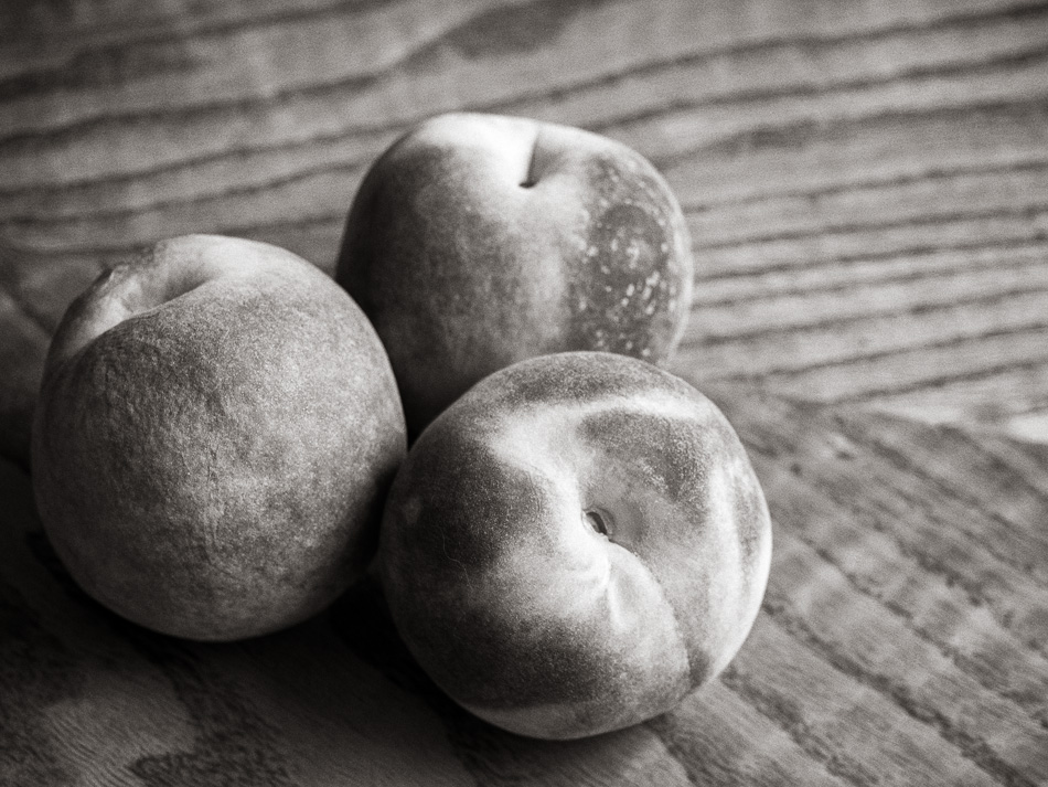 Black and white still life photo of three peaches on a table