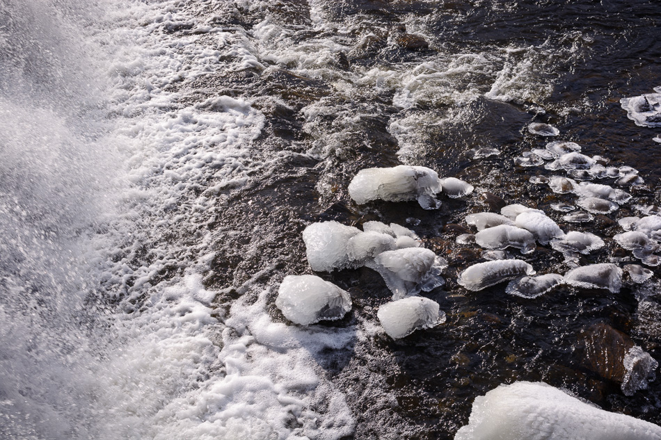 Color photo of turbulent water meeting icy rocks at the base of a waterfall on the Ashuelot River in Keene, NH