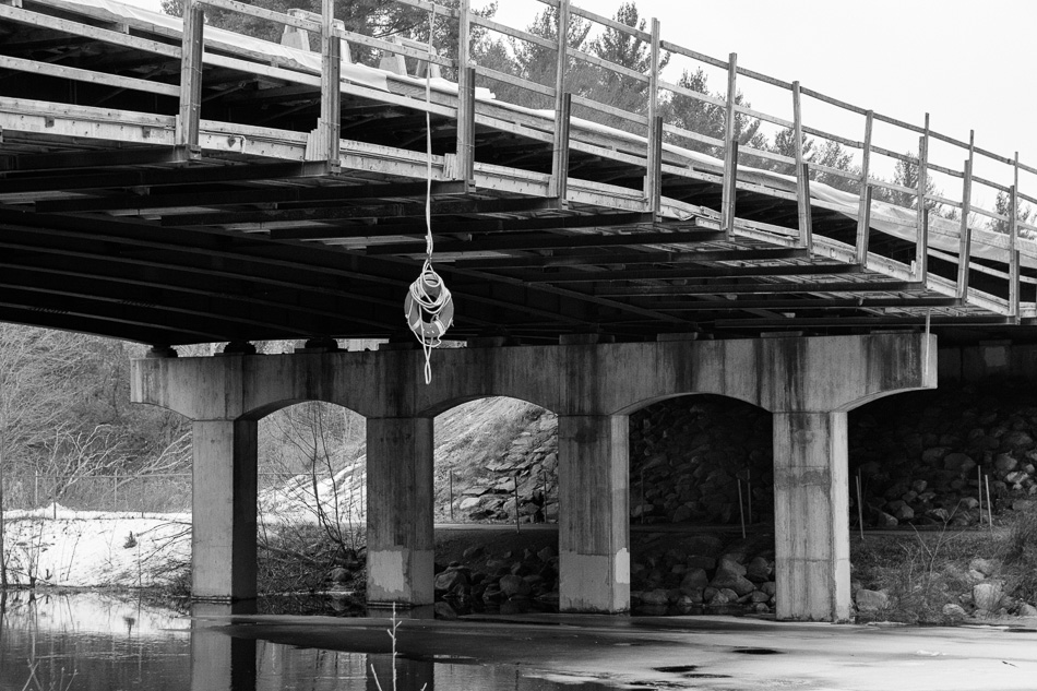 Black and white photo of a life preserver hanging from the Route 9 bridge over the Ashuelot River