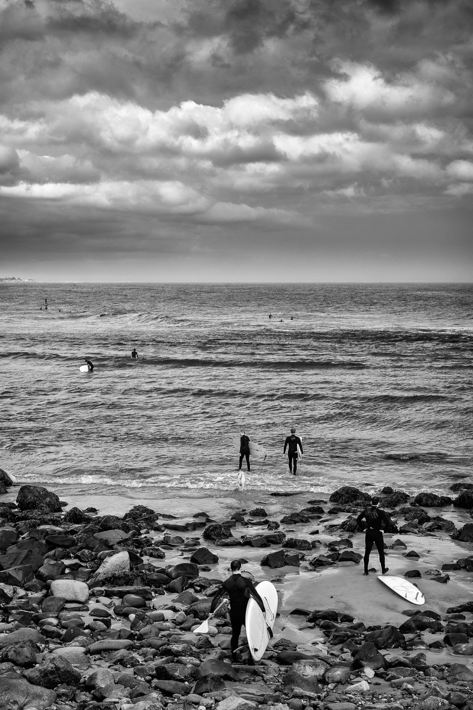Black and white photo of surfers entering the Atlantic Ocean off the Marginal Way