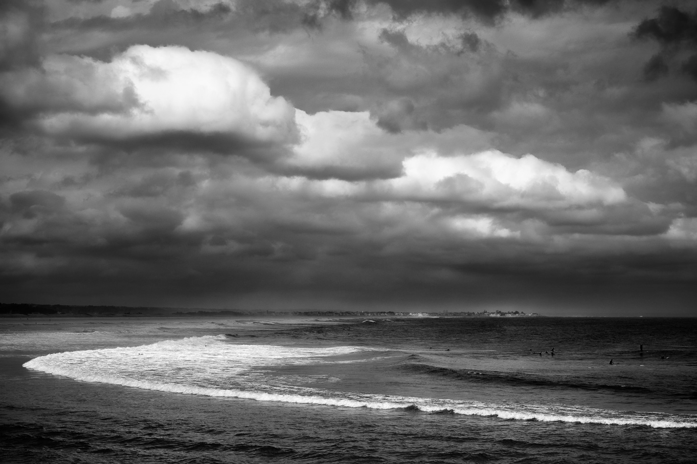 Black and white photo of clouds and surfers in Ogunquit, ME