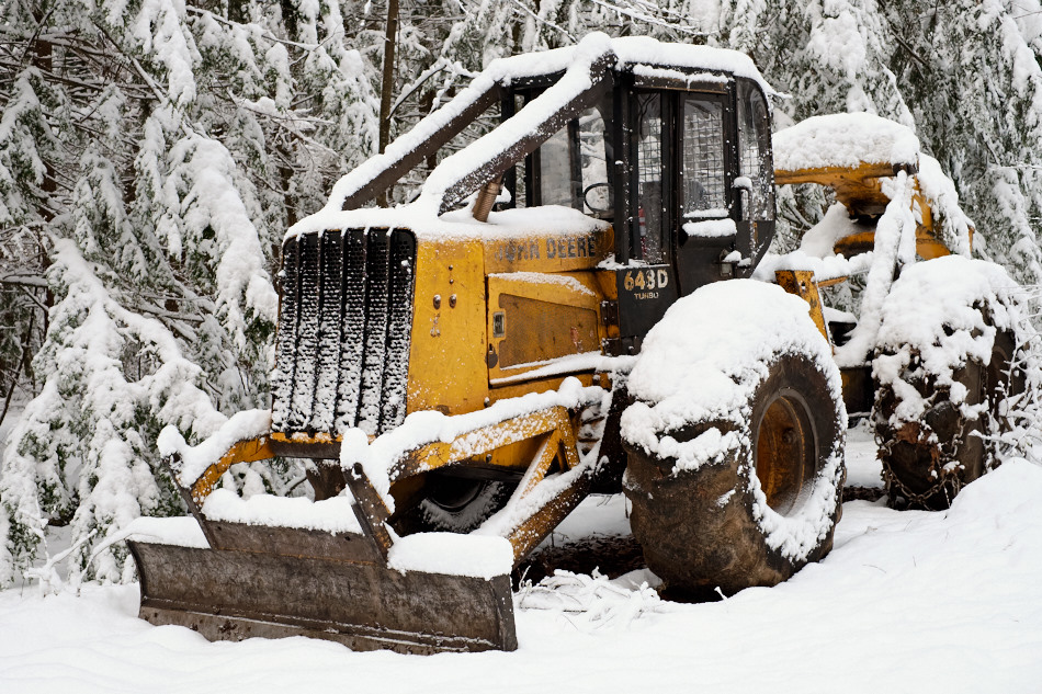 Color photo of a John Deere 648D in a snow covered forest