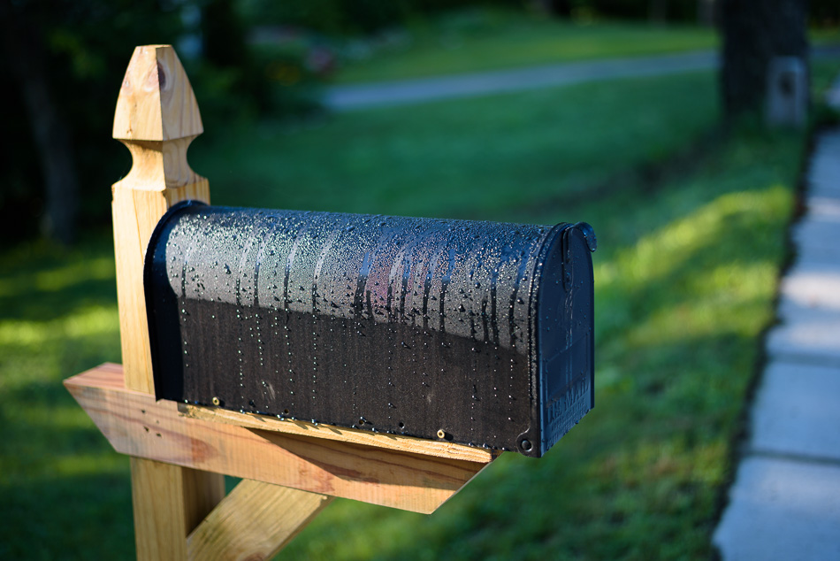 Color photo of dewdrops covering a black mailbox
